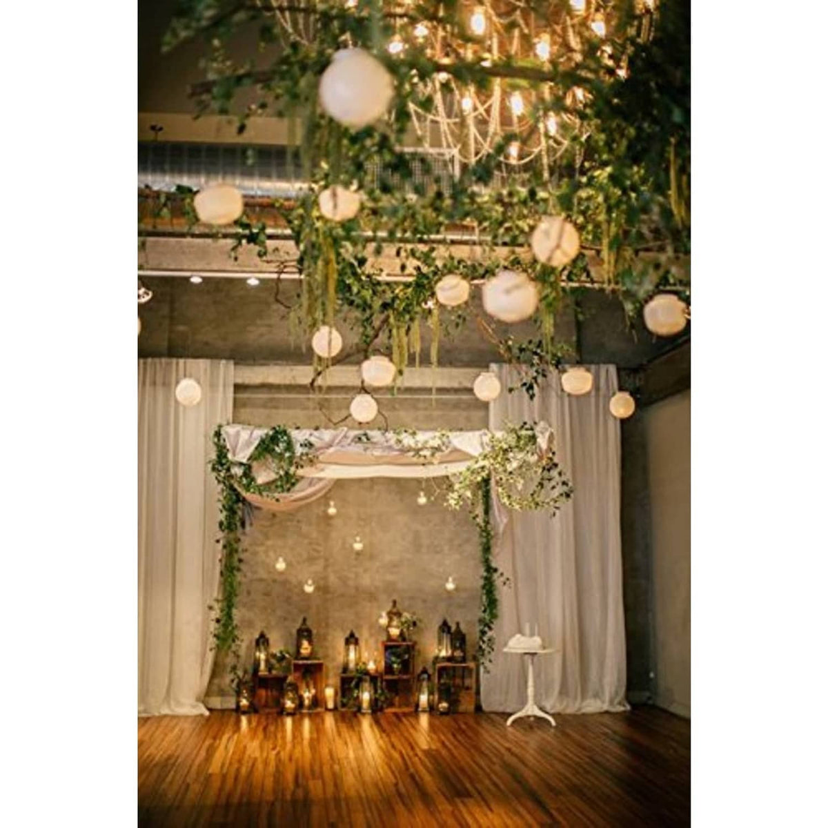 Multiple hanging white round paper lanterns at event decor with string lights in background