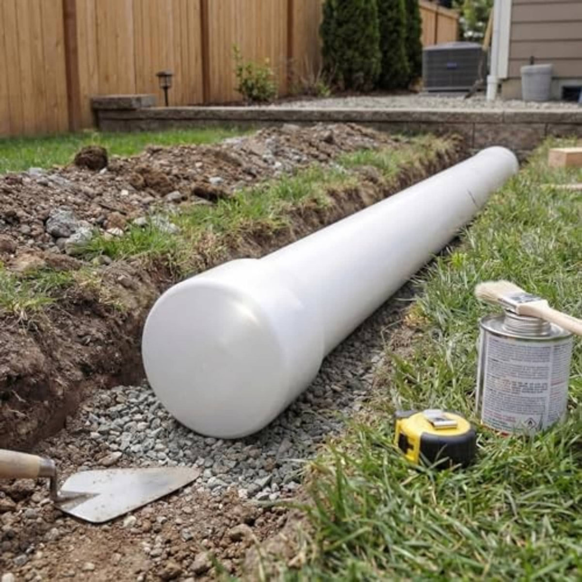 White PVC pipe end cap covering the end of a PVC pipe, outdoor install