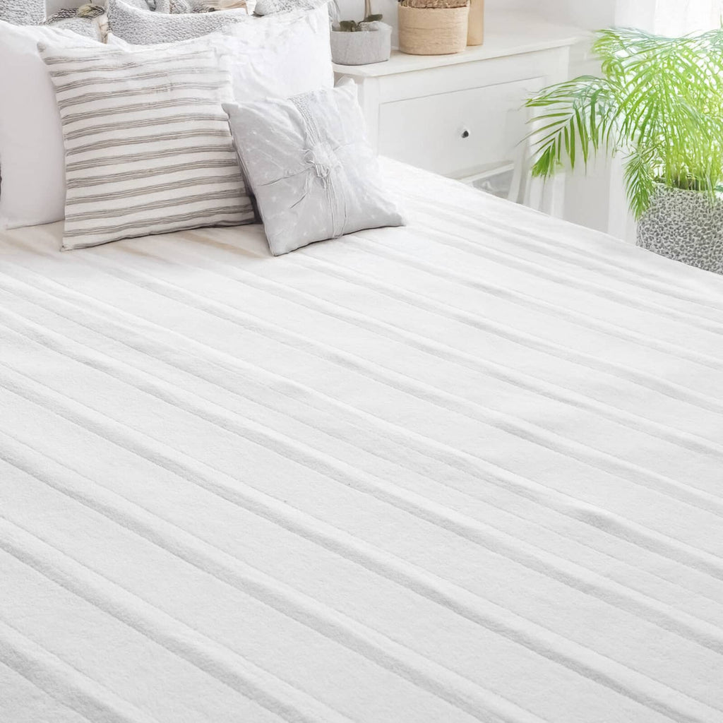 White heated mattress pad laid flat on a bed
