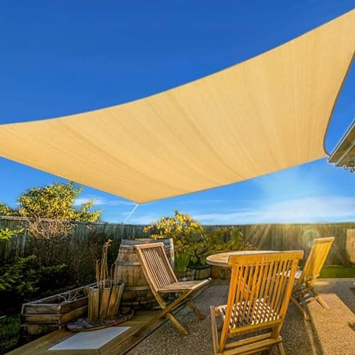 Sand sun shade sail stretched over patio seating, curved corners and grommets visible