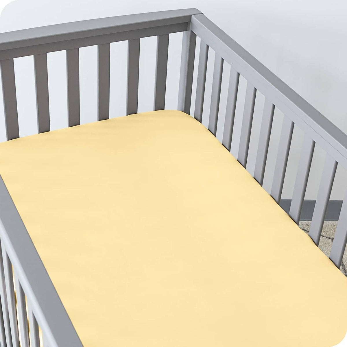 Yellow crib fitted sheet on mattress, smooth microfiber surface