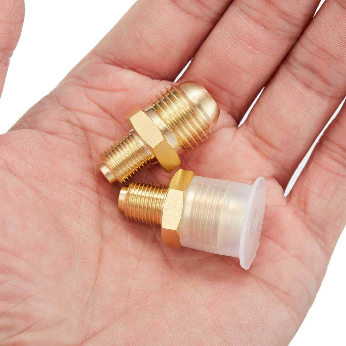 Brass propane orifice connectors held in palm, showing two flare-to-MNPT fittings