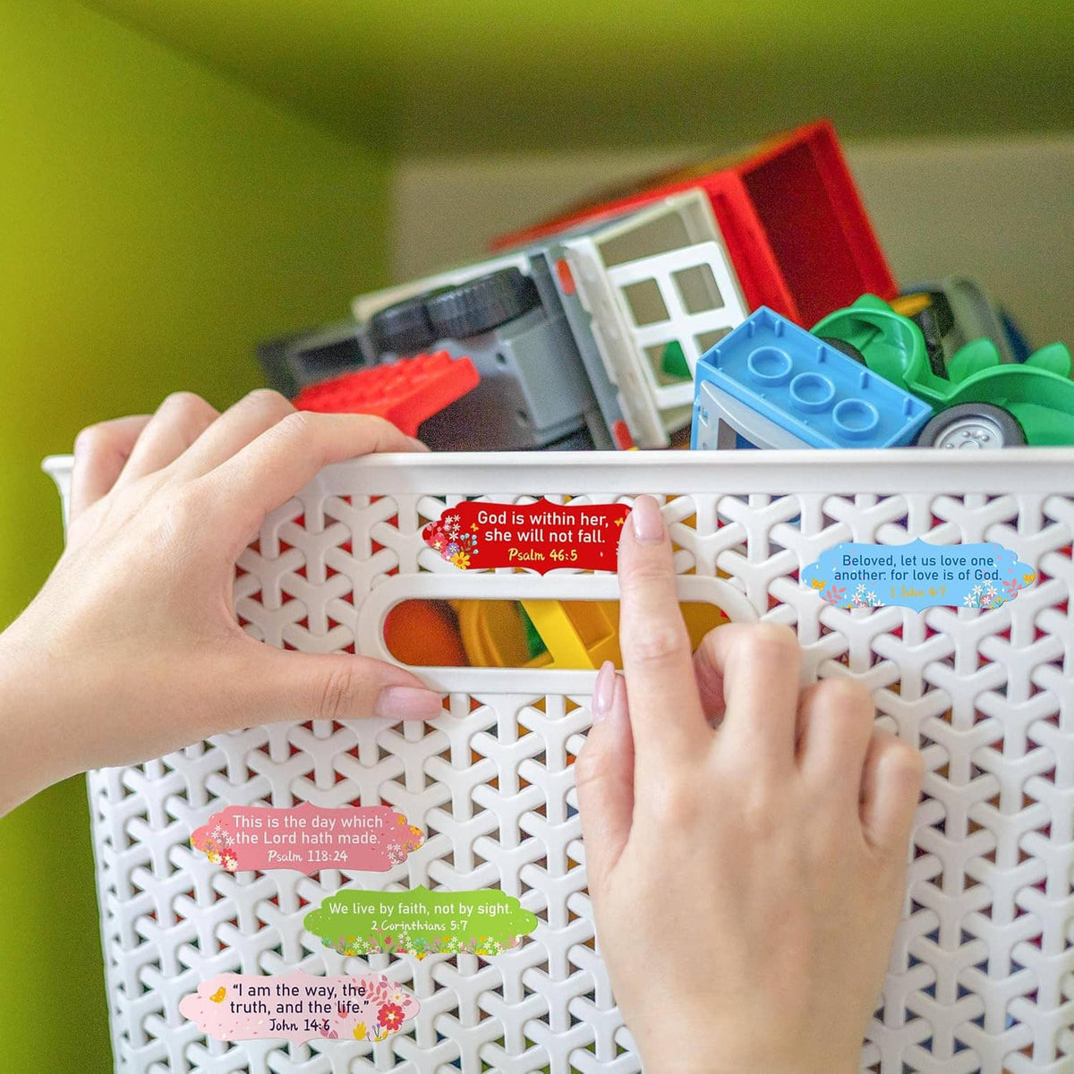 Bible verse stickers on a white lattice organizer shelf, held by hands