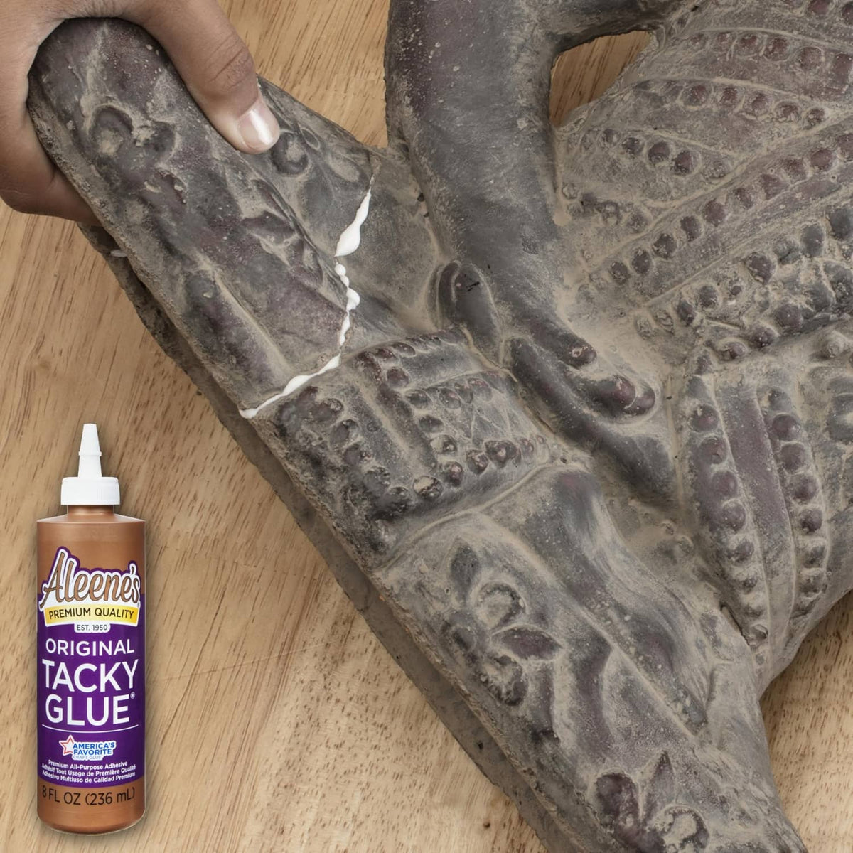 Person applying tacky glue to fabric craft; small bottle in view
