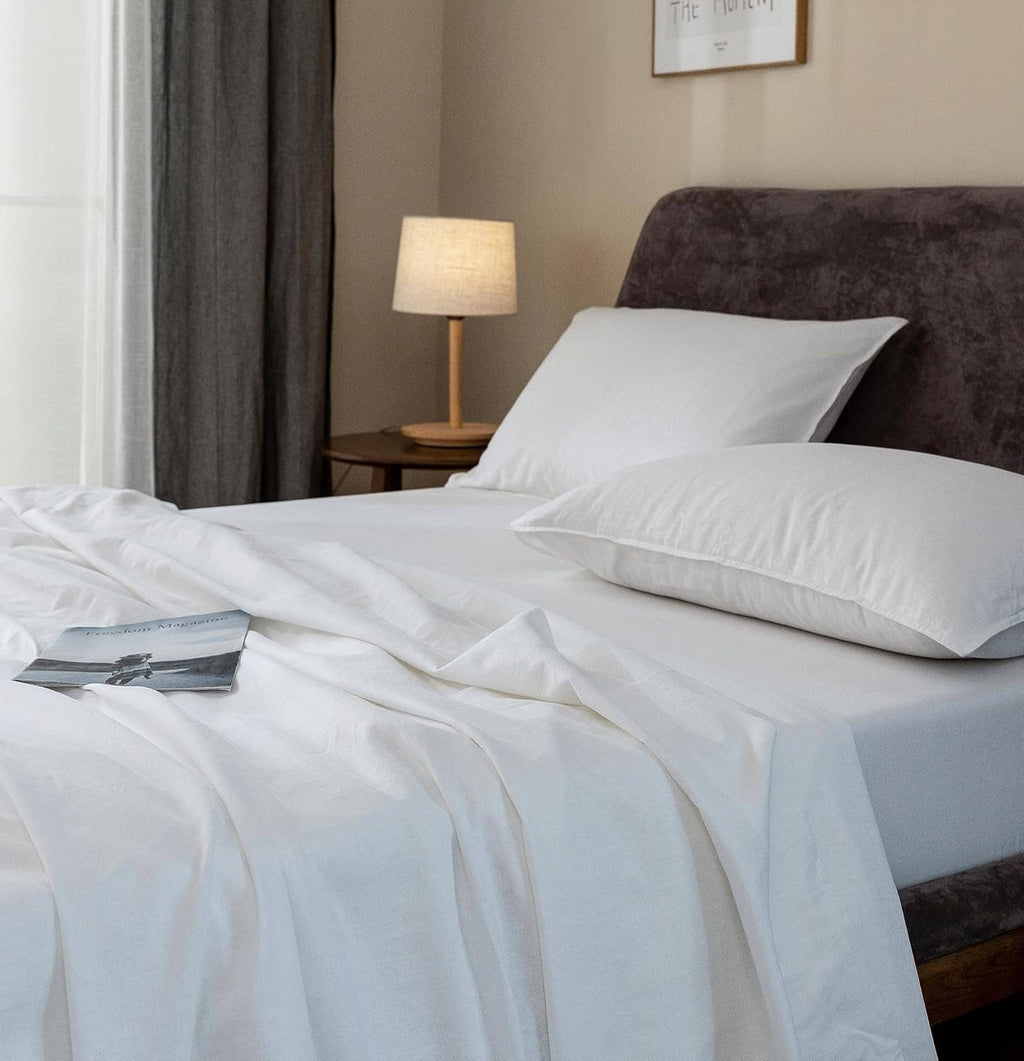 White linen sheets and pillowcases with visible textured folds and creases