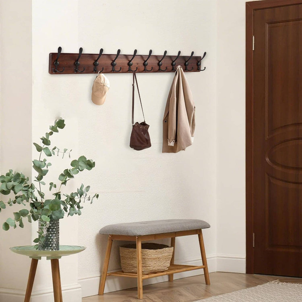 Wall-mounted coat rack with 10 black hooks, dark wood board, holding bags and coats