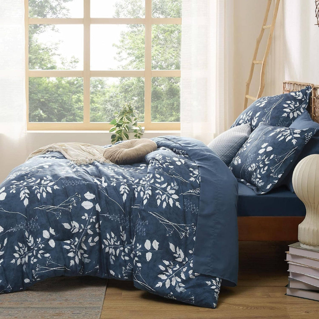 Navy floral comforter set with pillows arranged on a queen bed near large windows