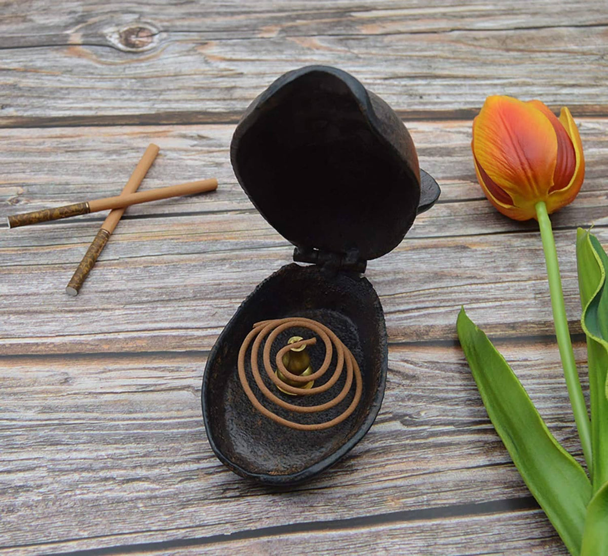 Monkey-shaped cast ashtray with hinged open lid and cigarette coils inside