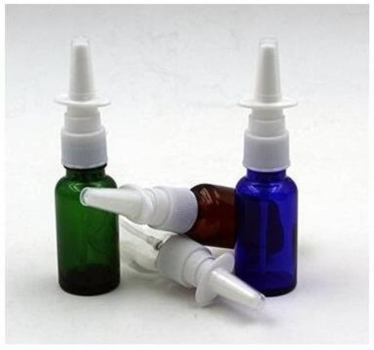Green and amber glass nasal bottles with white pump nozzle tips and applicators