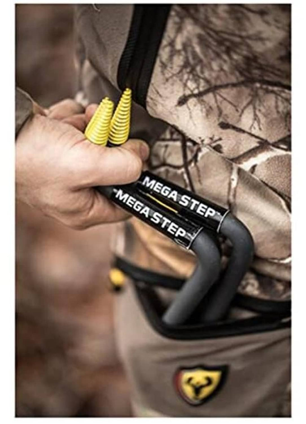Hand holding black tree step tool labeled MEGA STEP with yellow screw coil