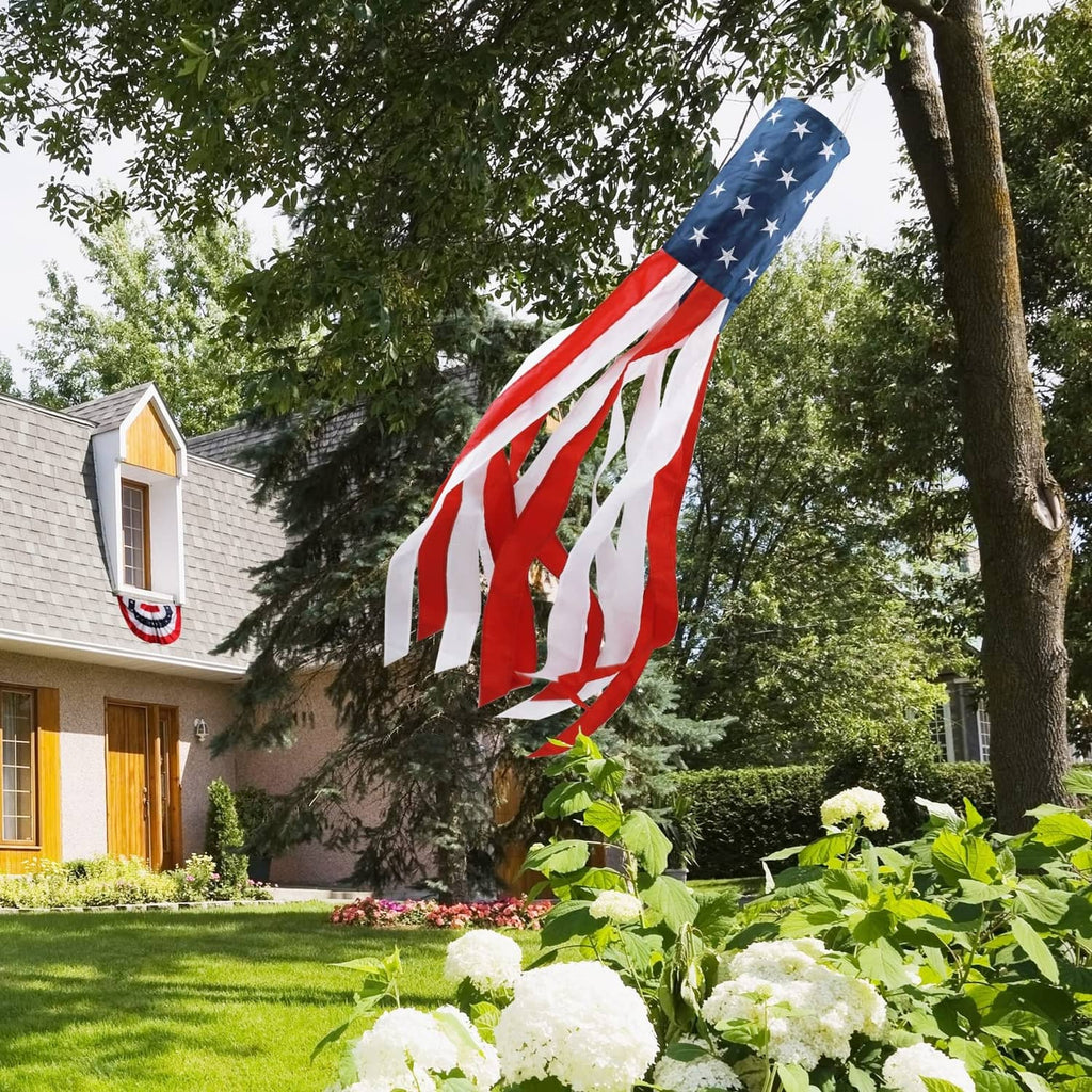 US flag windsock hanging outdoors from a tree branch above a garden lawn