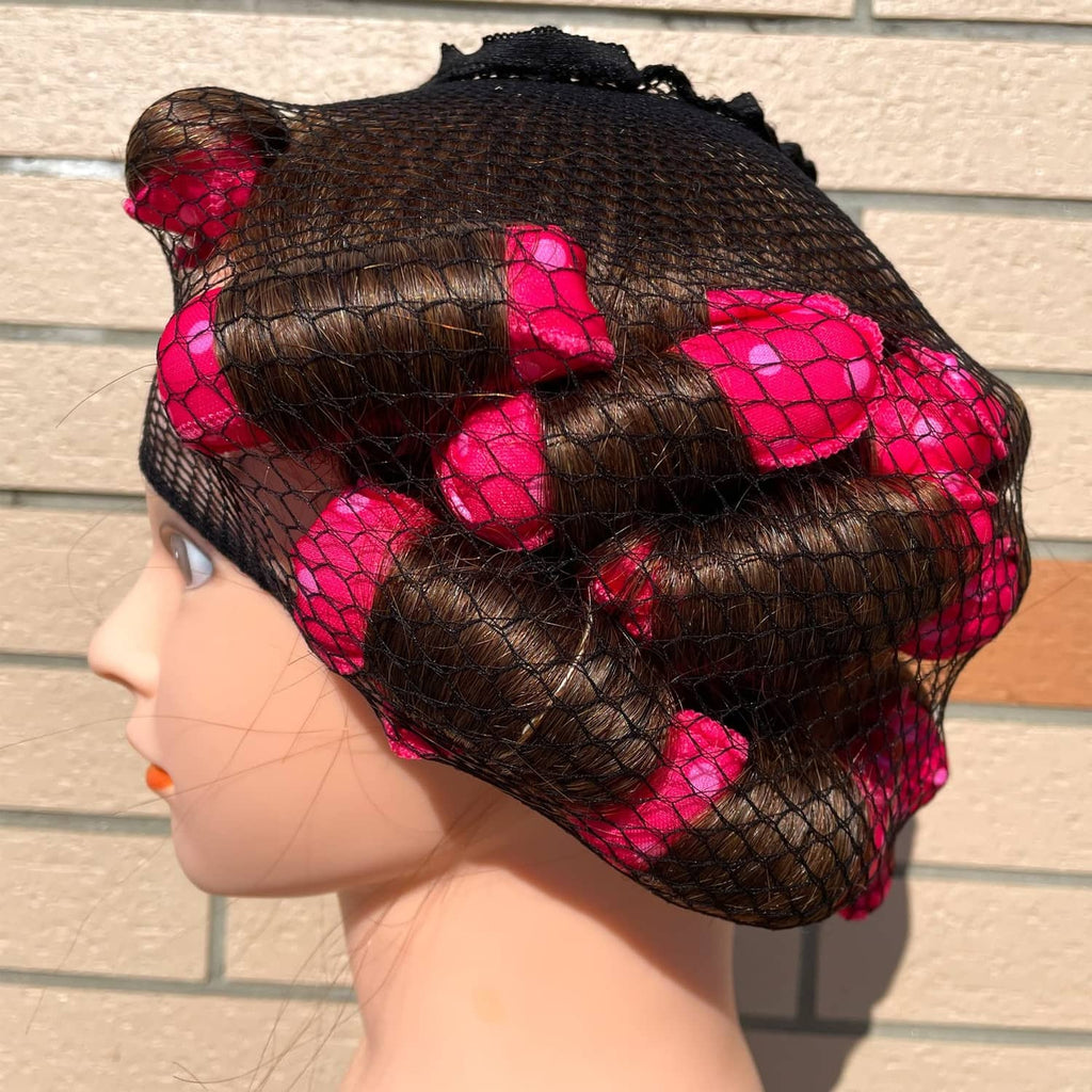 Black mesh hair cap holding pink polka-dot curlers on dark hair