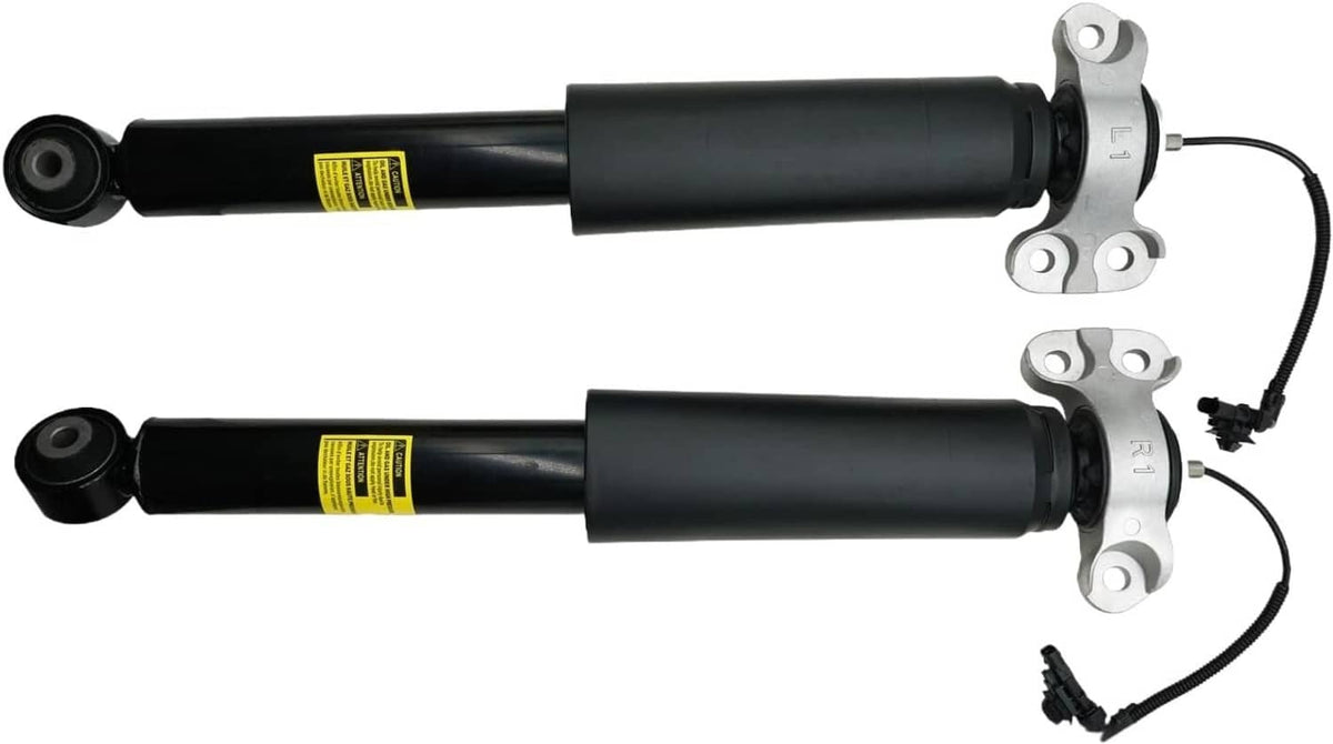 Pair of black rear shock absorber struts with yellow labels, mounting plates, and wiring