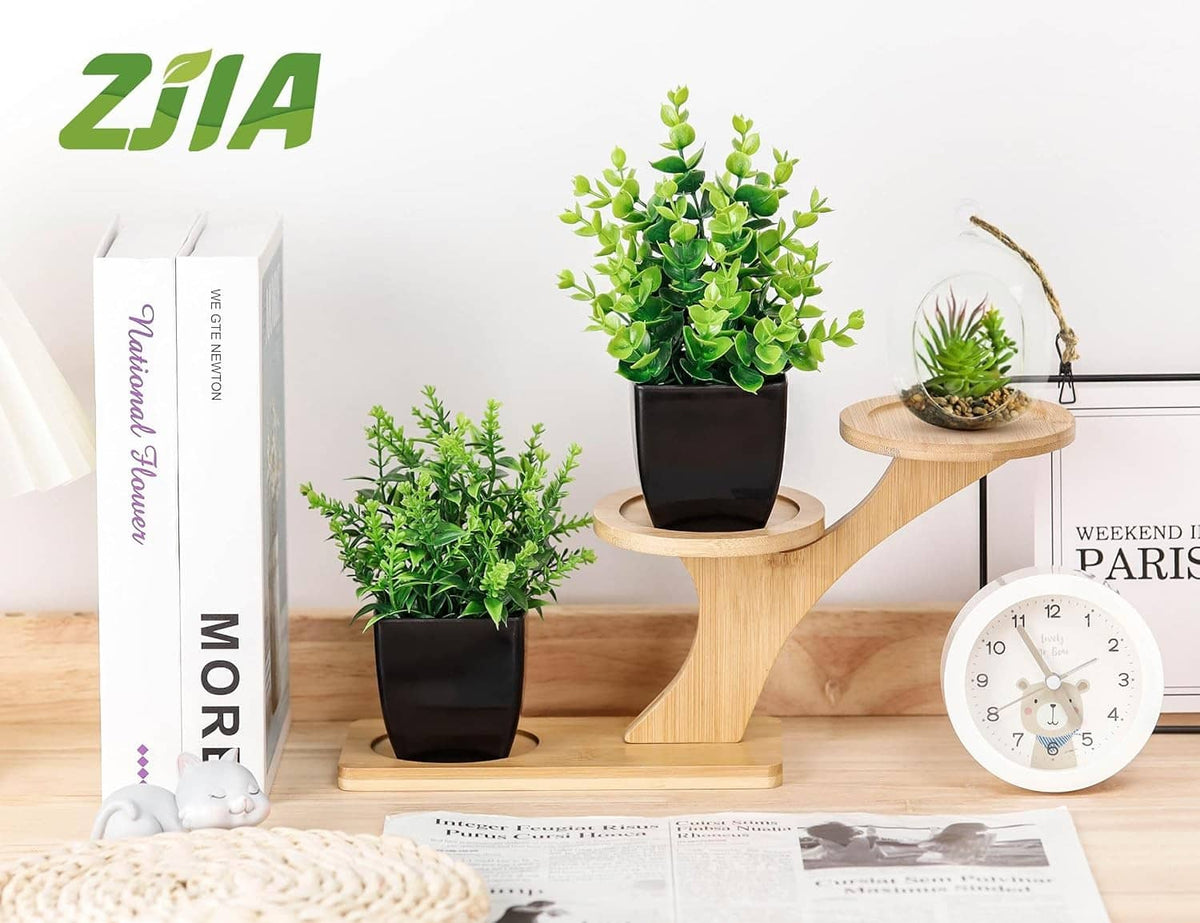 Two small faux plants in black pots with bright green leaves on display