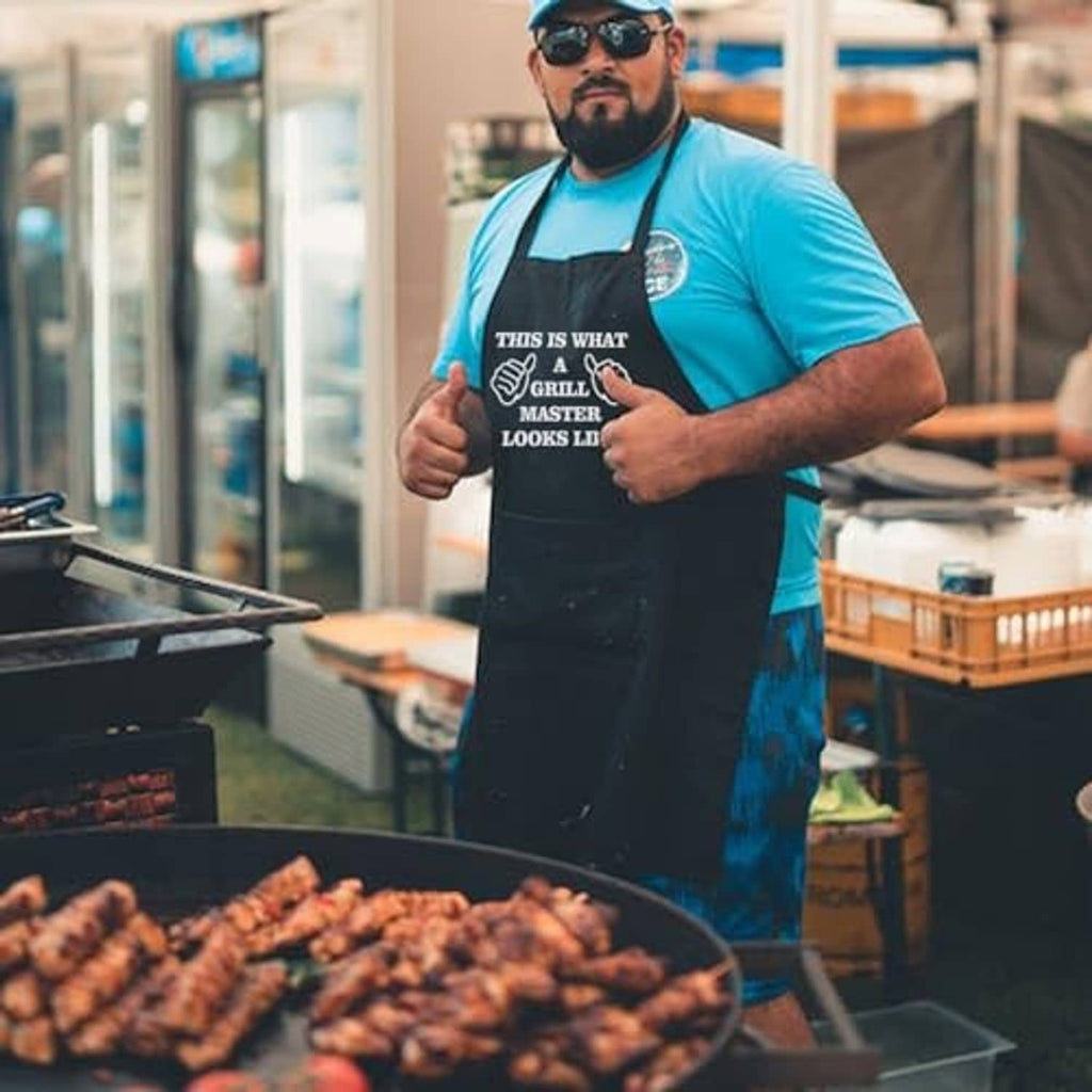 Black grilling apron worn by a man with “Grill Master looks like” graphic