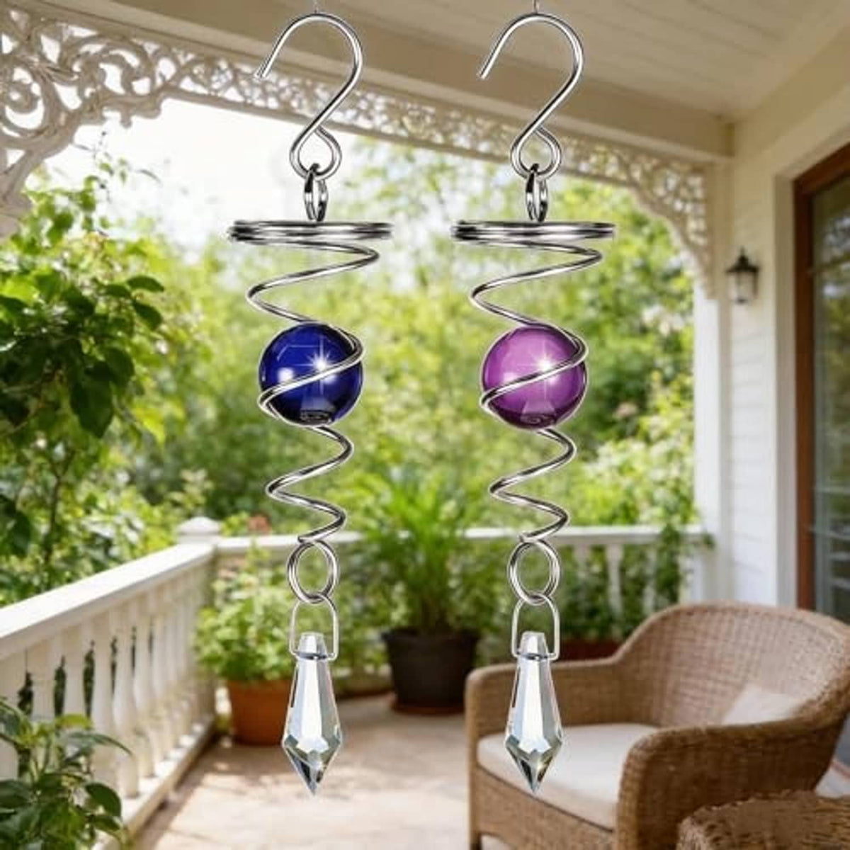 Two hanging stainless steel wind spinners with blue and purple spheres and clear crystal drops