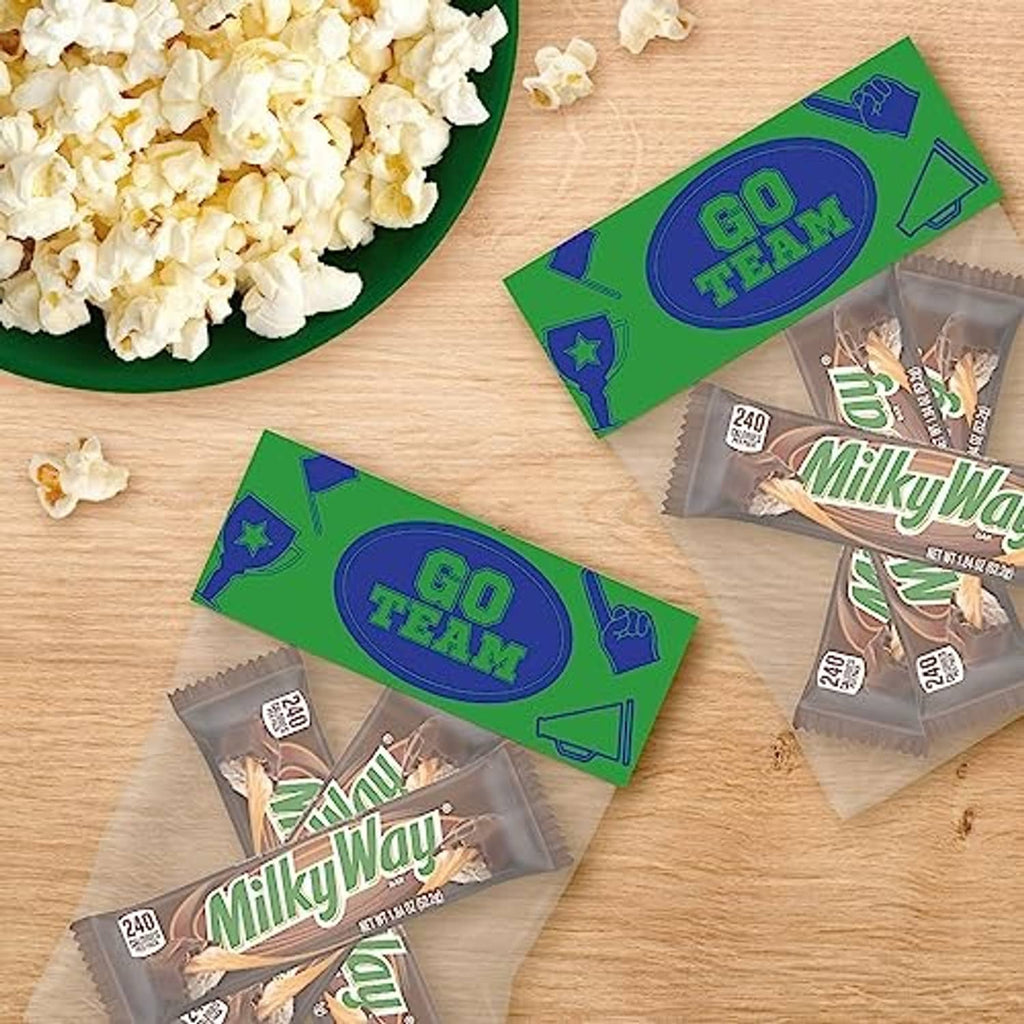 Milky Way bars in wrappers laid on wooden table with popcorn pieces