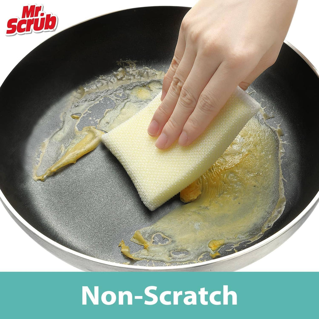 Non-scratch sponge in hand scrubbing a pan with pale yellow foam