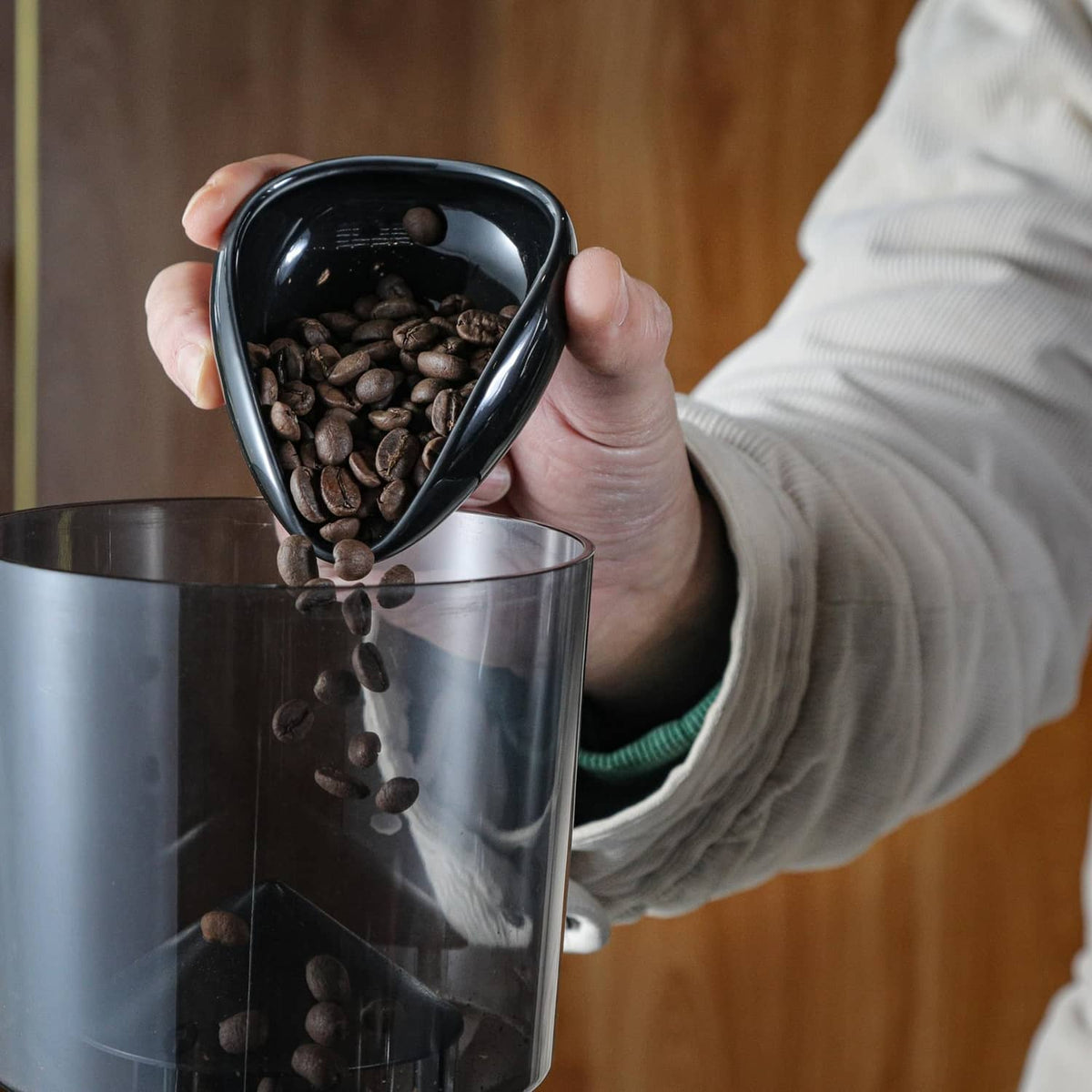 Coffee beans pouring from a black dosing cup using a black RDT sprayer