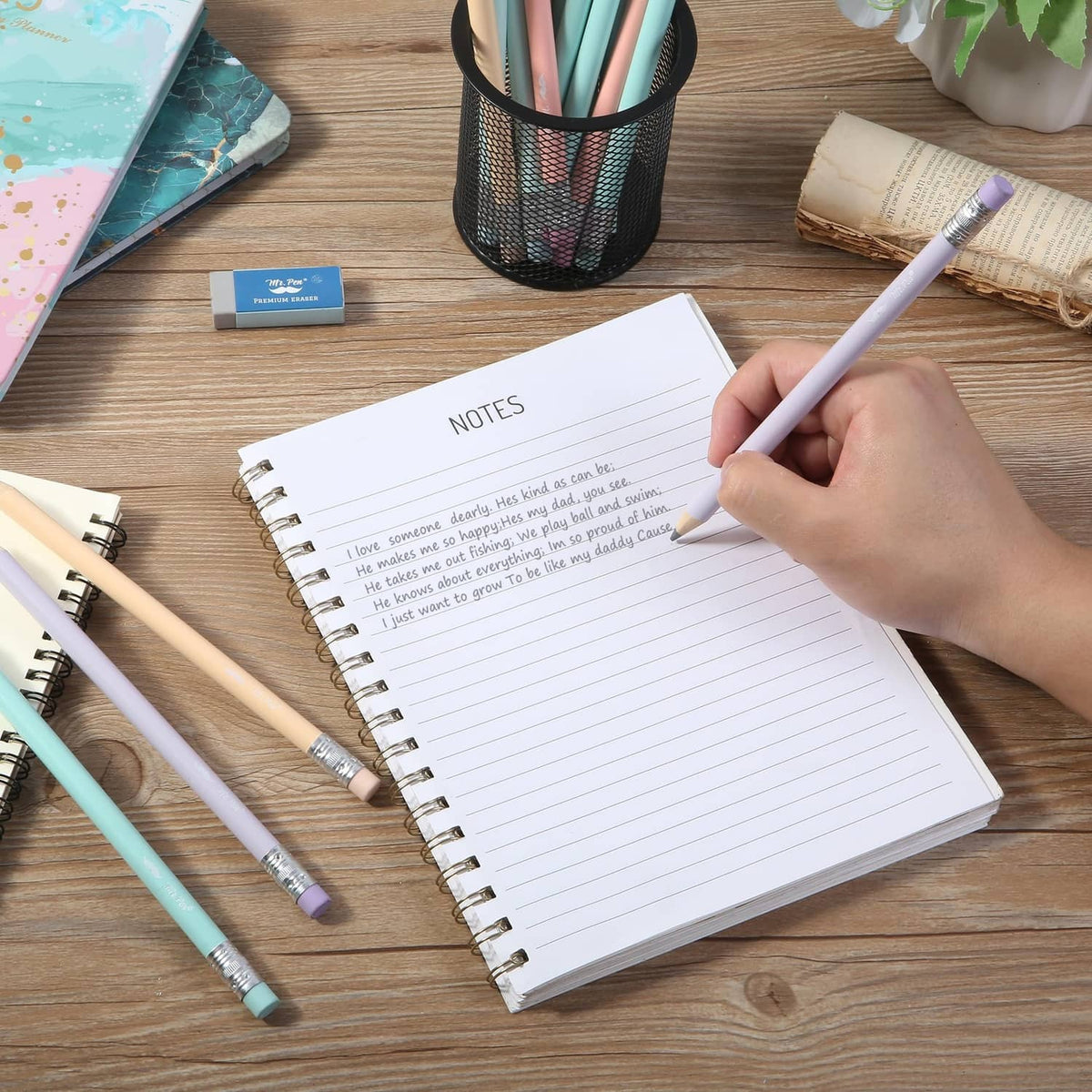 Pastel jumbo pencils with sharpened tips, one pencil in a hand writing on paper