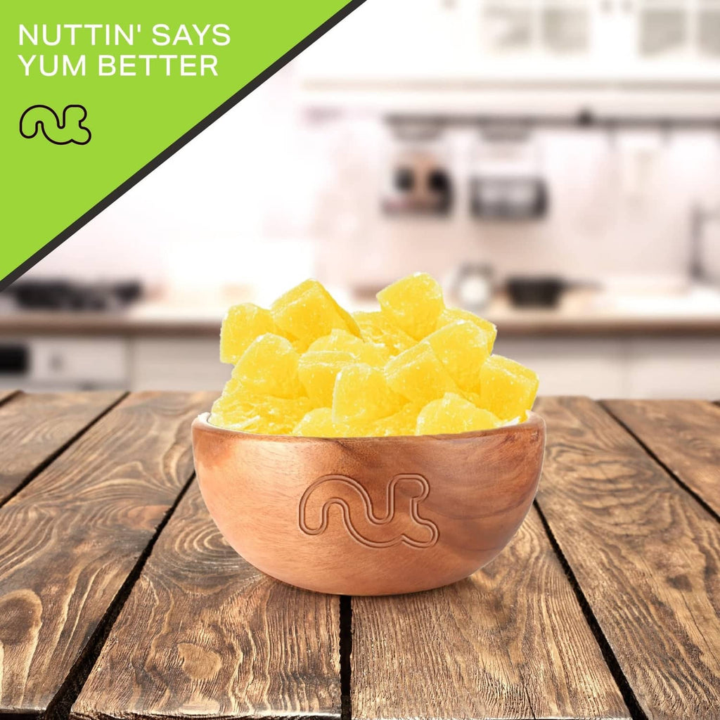 Bowl filled with dried pineapple chunks with sugar added on a wooden table