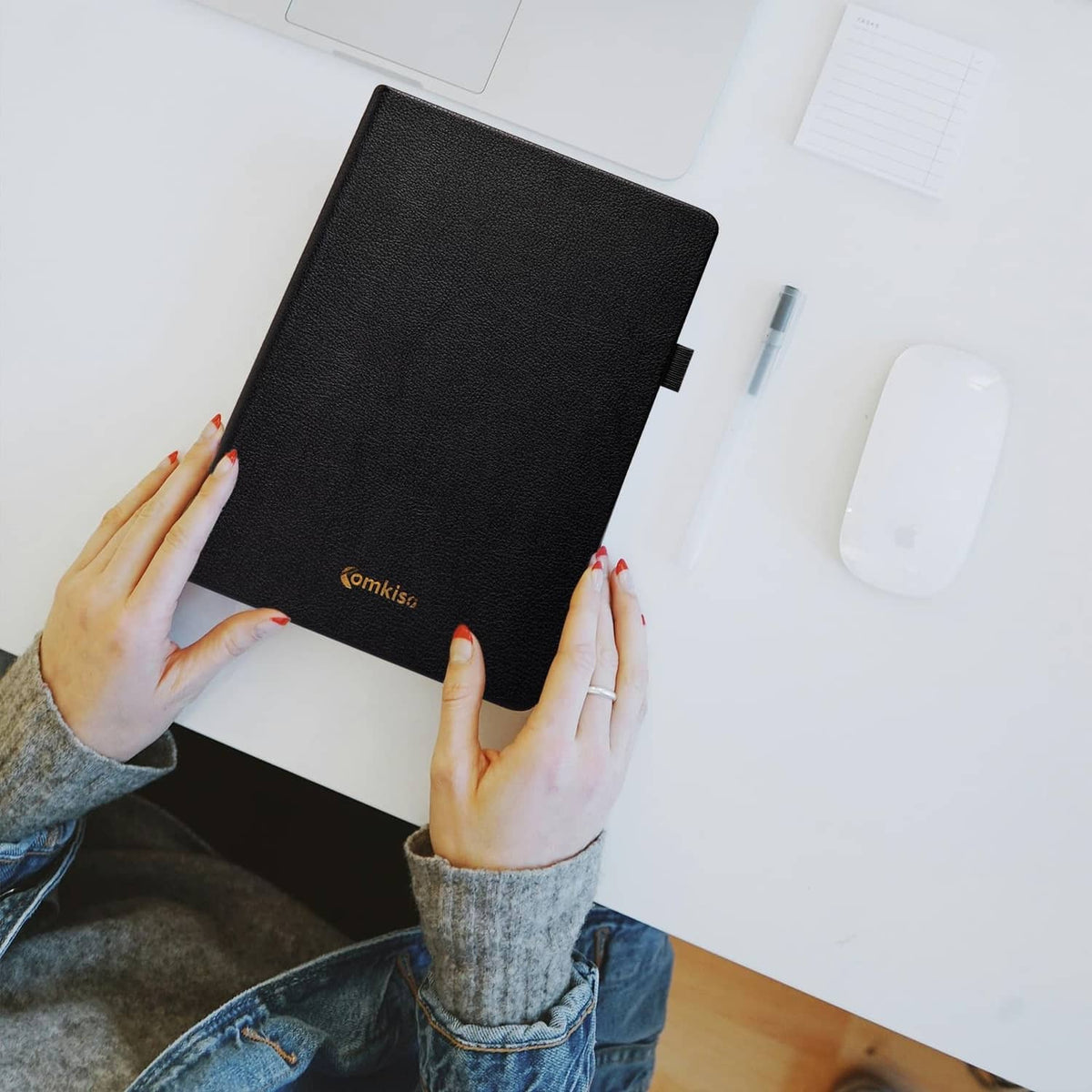 Black password notebook held on desk, with textured cover and elastic closure.
