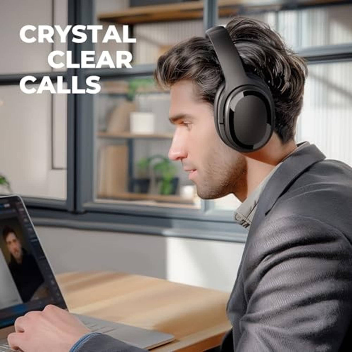 Black over-ear wireless headphones on a person working at a desk