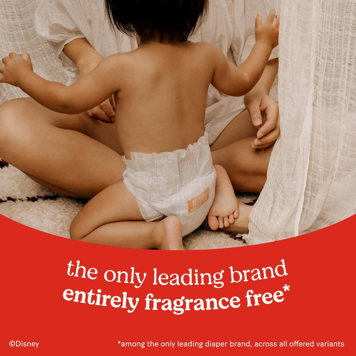 White diaper on baby, front tabs visible, Skin Essentials fragrance-free claim