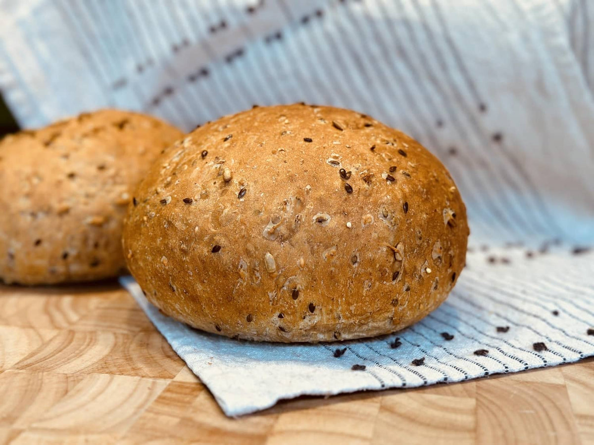 Round 8 grain bread rolls with seeded crust on a striped cloth