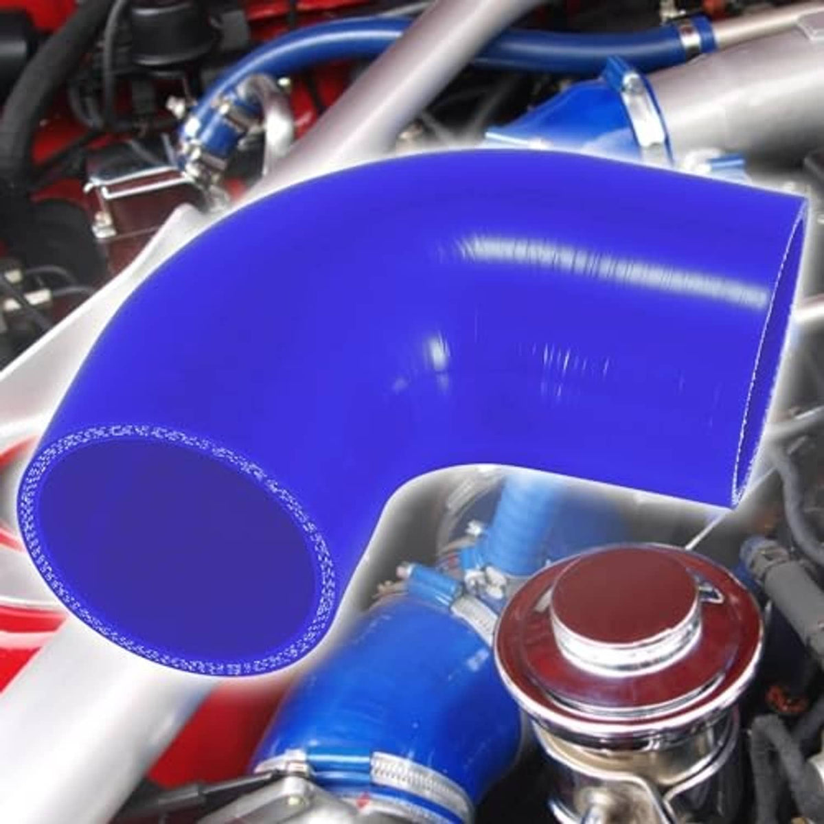 Blue 90-degree silicone hose elbow installed with nearby metal clamps and fittings