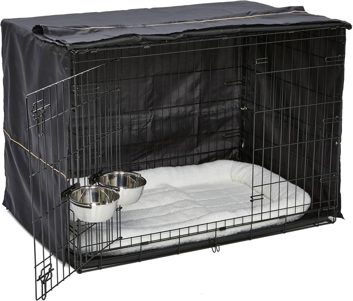 Black double-door dog crate with white fleece pad and stainless bowls inside