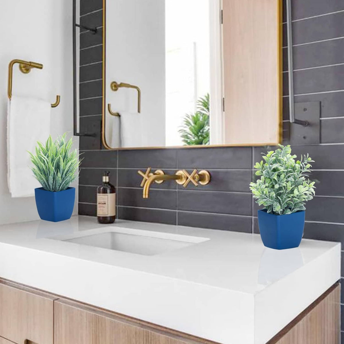 Two potted artificial plants in blue pots on bathroom counter: leafy and spiky
