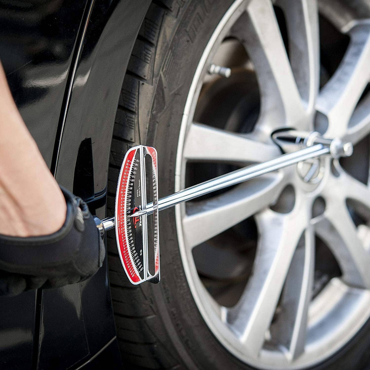 Torque wrench applying to tire wheel lug area with red scale