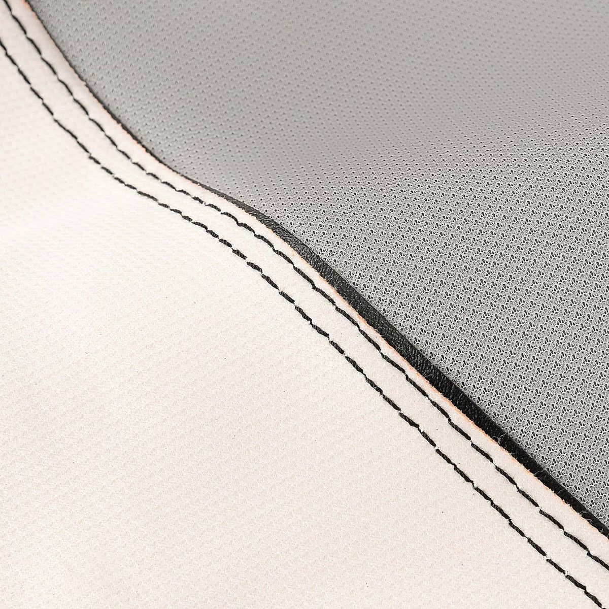Seat cover stitching close-up, white surface with black trim and double-stitched seam