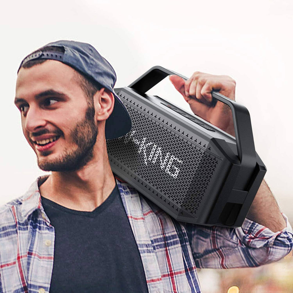 Black portable Bluetooth speaker held in front, with carry handle and grille