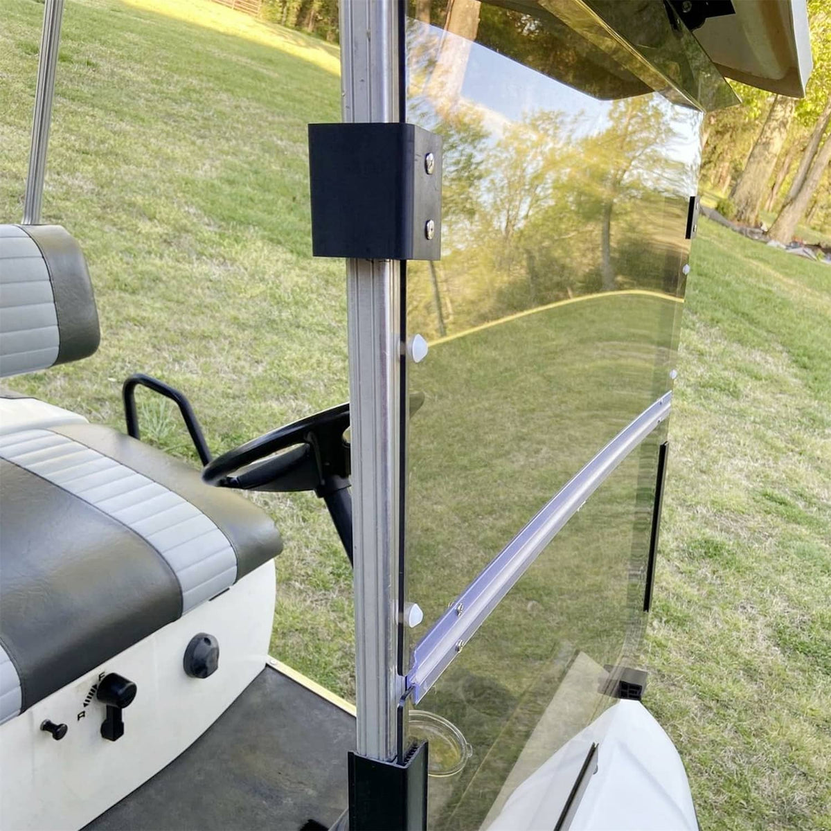 Tinted folding golf cart windshield side view with front posts and black hinge block