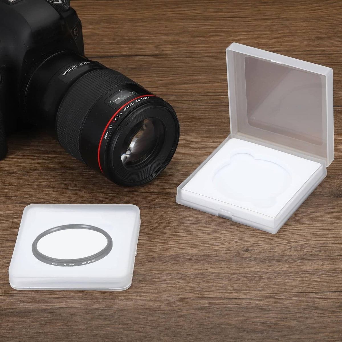 67mm lens filter case on tabletop beside camera lens, white insert inside