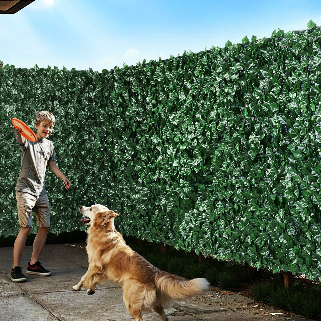 Artificial faux ivy privacy fence wall with dense dark green leaves along a walkway
