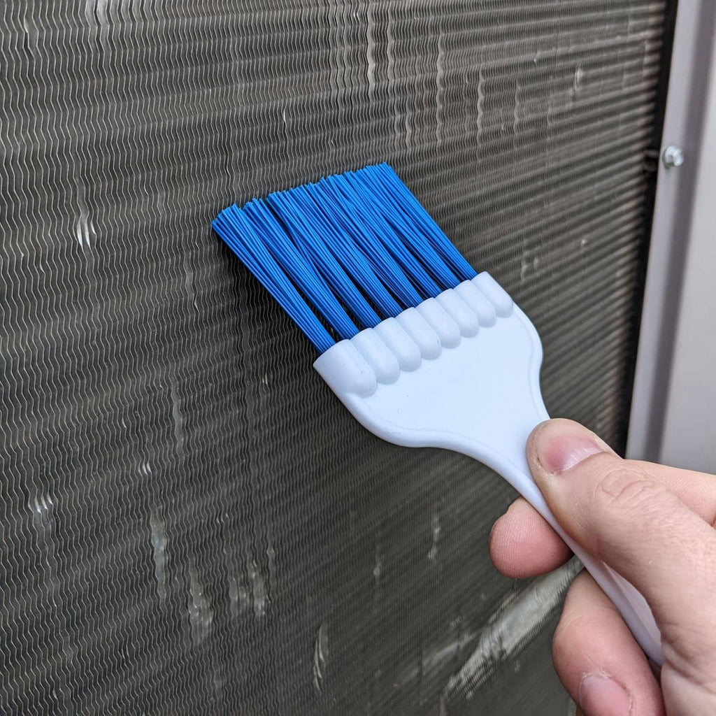 Handheld coil cleaning brush with blue bristles scrubbing a metal grille