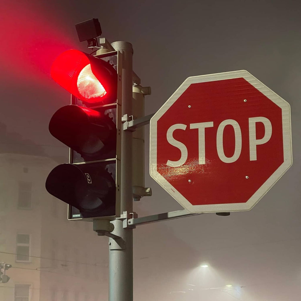 Octagonal red STOP sign with white letters near traffic lights