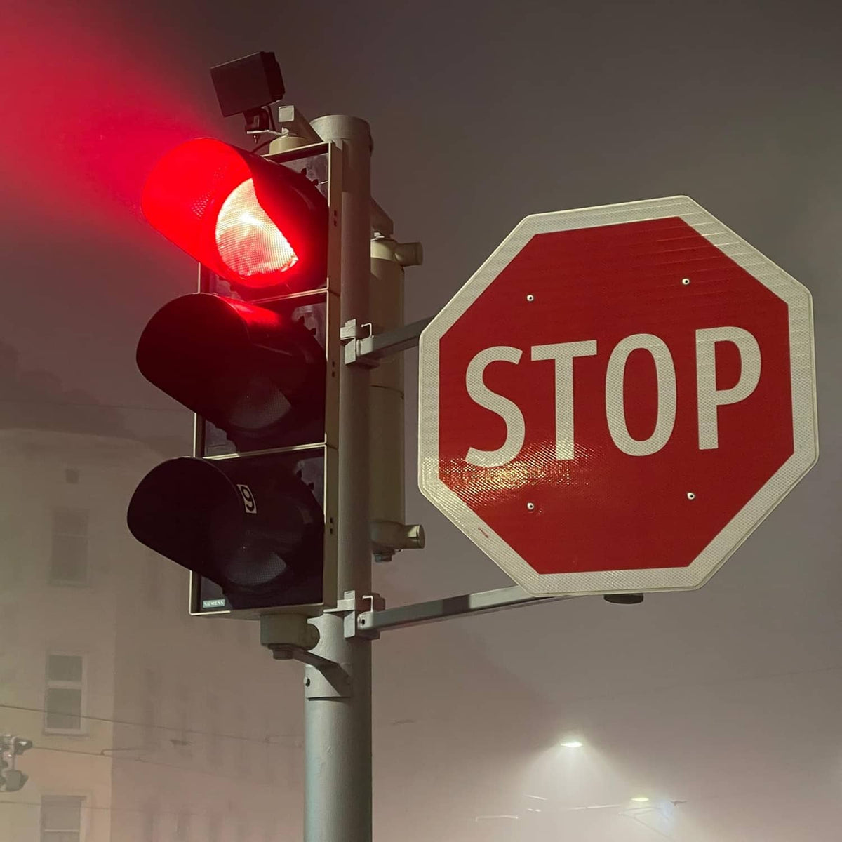 Octagonal red STOP sign with white letters near traffic lights