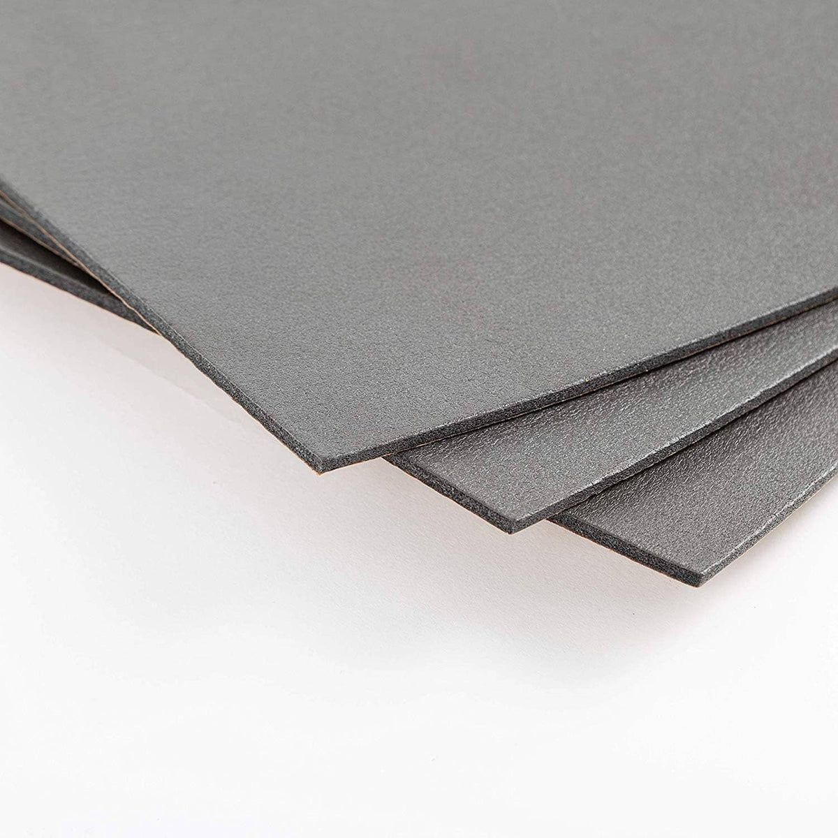Layered dark gray sound insulation sheets with narrow brown adhesive border