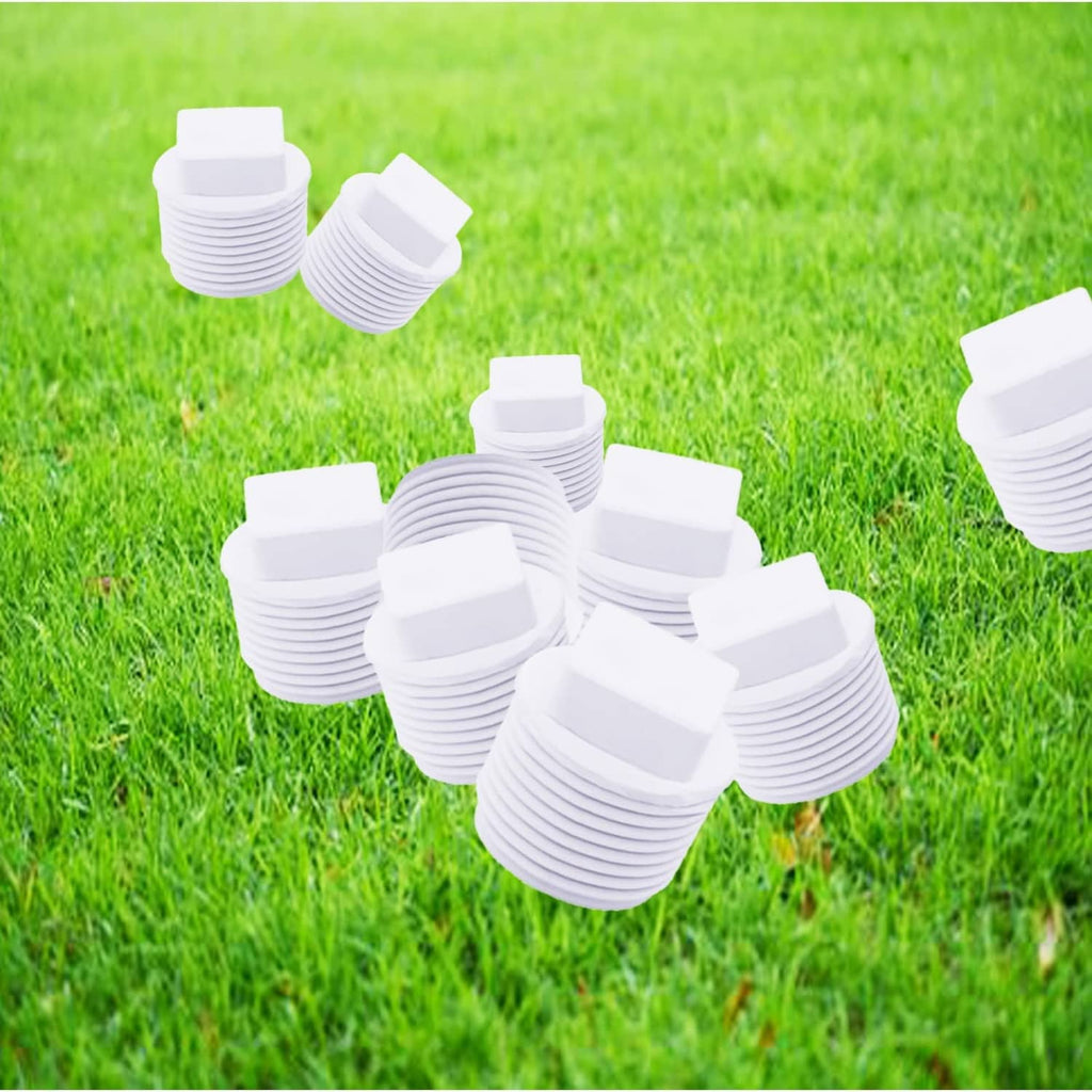 White PVC threaded plug caps for pipe ends, scattered on green grass