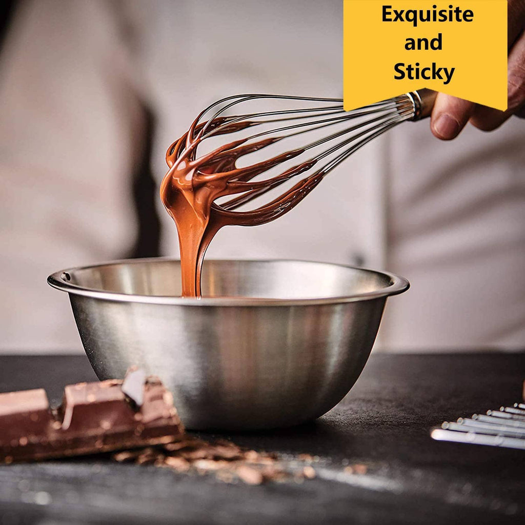 Stainless steel whisk pouring dark brown batter from a metal mixing bowl