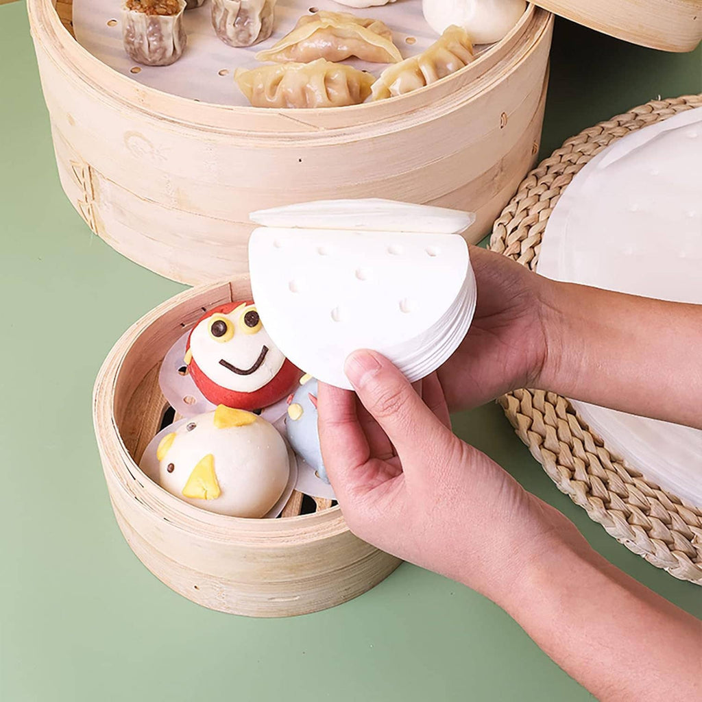 Hand placing a round perforated white steamer liner into a bamboo steamer basket