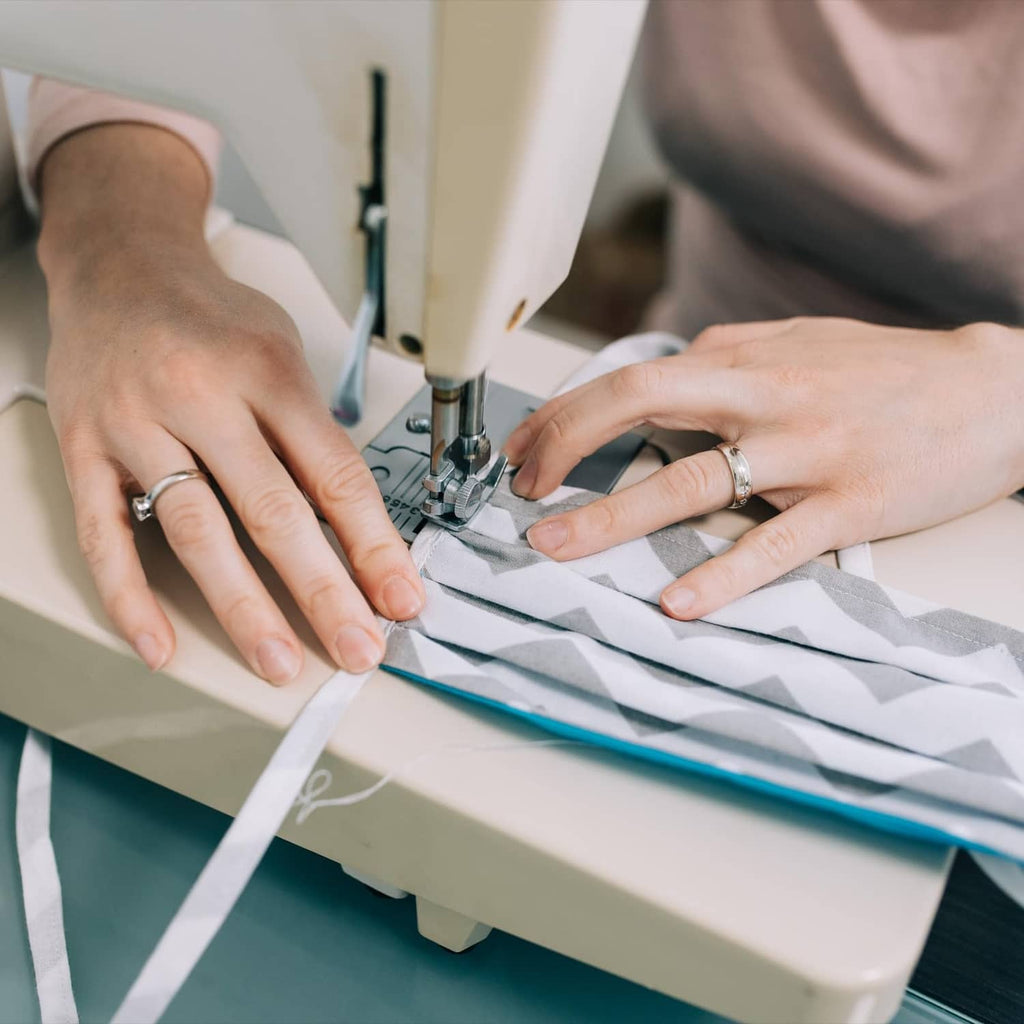 Double-fold bias tape stitching with a sewing machine, hands guiding fabric
