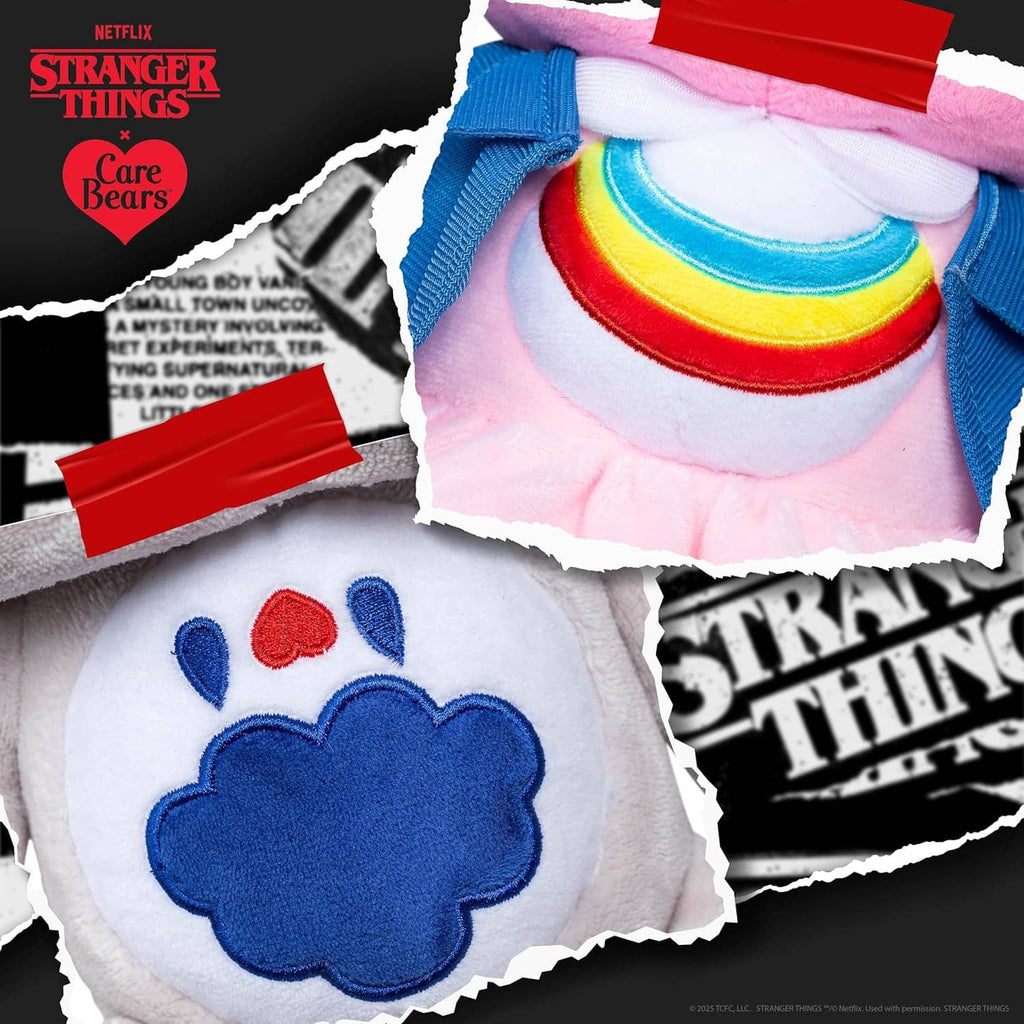 Close-up plush bear outfit details: rainbow collar and blue flower emblem