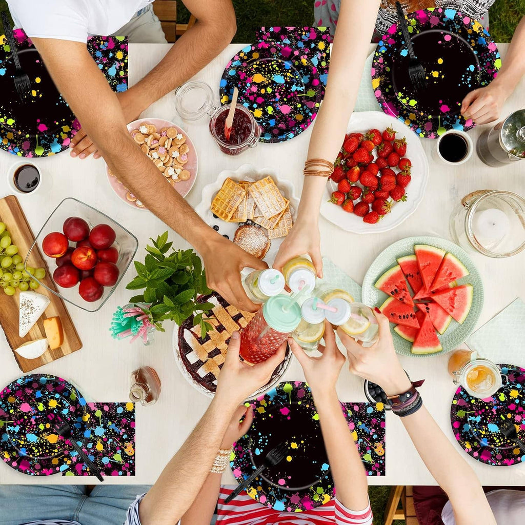 Neon splatter party plates and napkins on a table with drinks, fruit, and snacks