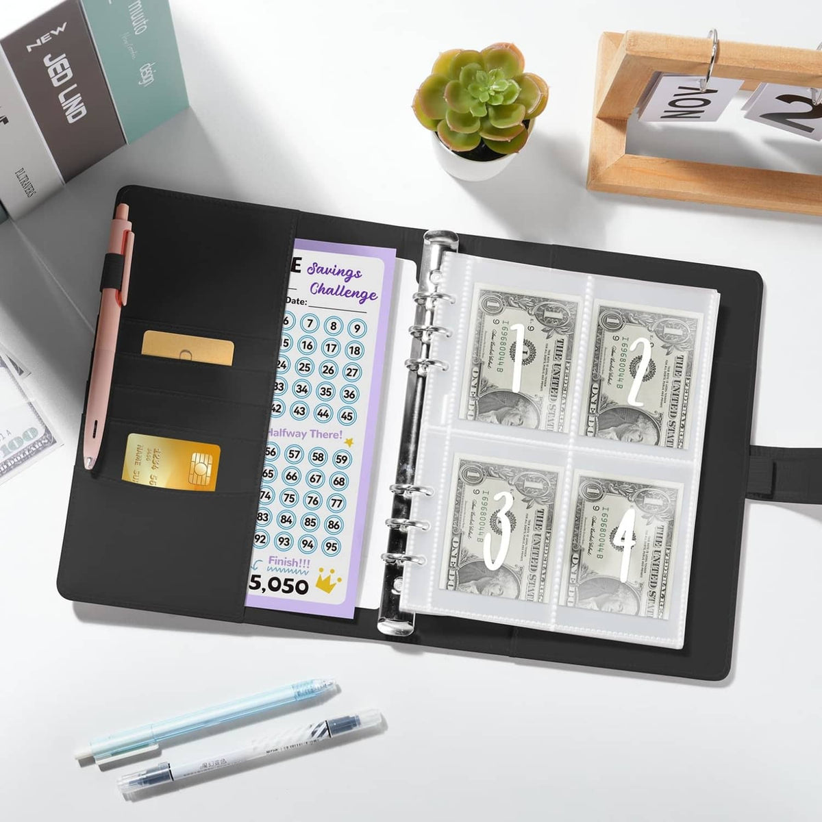 Black A5 binder open with transparent slots and numbered 1–4 cash envelopes