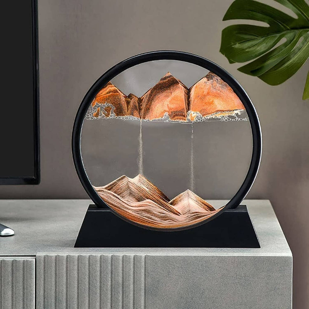 Dynamic sand art sphere with black frame and orange mountains, white stream in middle